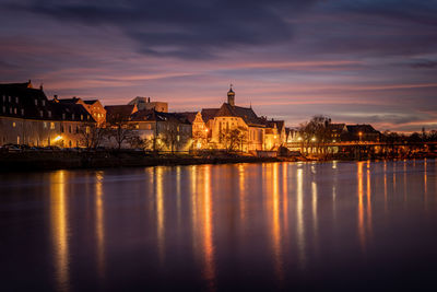 Reflection of illuminated buildings in city at sunset