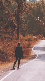 Rear view of man walking on road