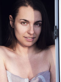 Portrait of beautiful woman standing by window at home