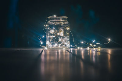 Close-up of illuminated glass jar on table