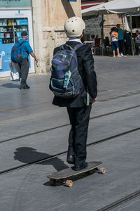 Rear view of men walking on footpath in city