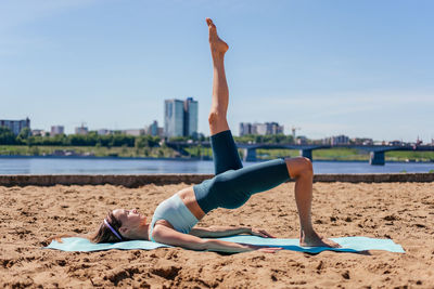 Full length of woman exercising at beach