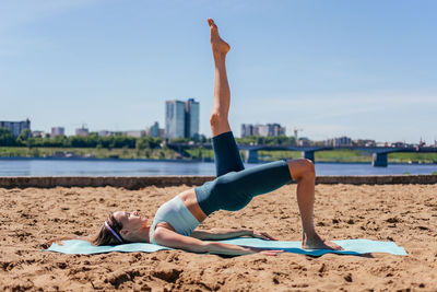 Middle aged woman in sportswear doing yoga exercise with raised leg outdoor. woman stretching