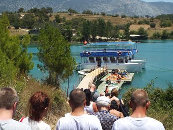 Rear view of people standing by lake against sky