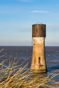 Lighthouse on sea against sky