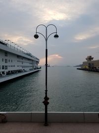 Street light by sea against sky during sunset