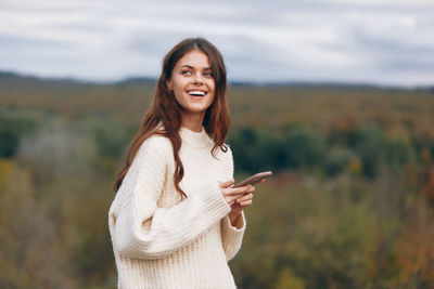 Young woman looking away while standing on field