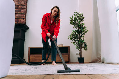 Full length portrait of woman standing against wall at home