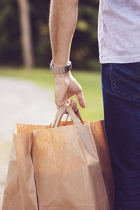 Cropped image of man carrying brown bags
