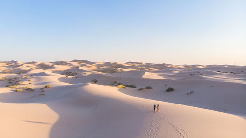 High angle view of couple walking on sand at desert against sky