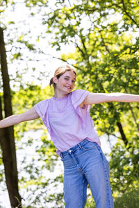 Portrait of young woman standing against trees