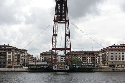 Bridge over river in city against sky