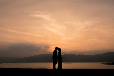 Silhouette of couple facing each other in front of sea