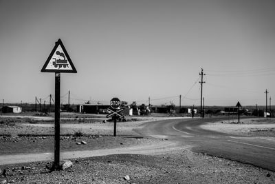 Road sign by street against sky