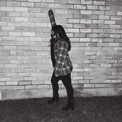 Full length of woman standing against brick wall