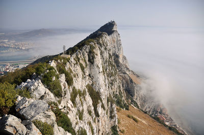 Scenic view of sea by mountain against sky