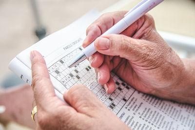 Cropped hands solving puzzle on newspaper