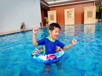 Smiling boy with inflatable ring swimming in pool