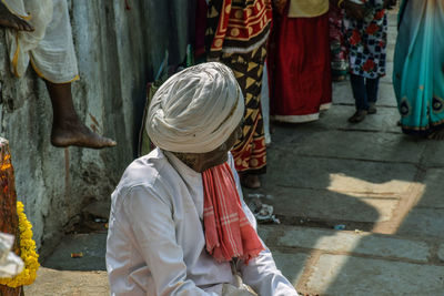 Senior man in turban sitting outdoors at market