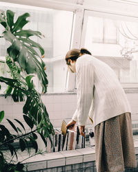 Side view of woman standing against window