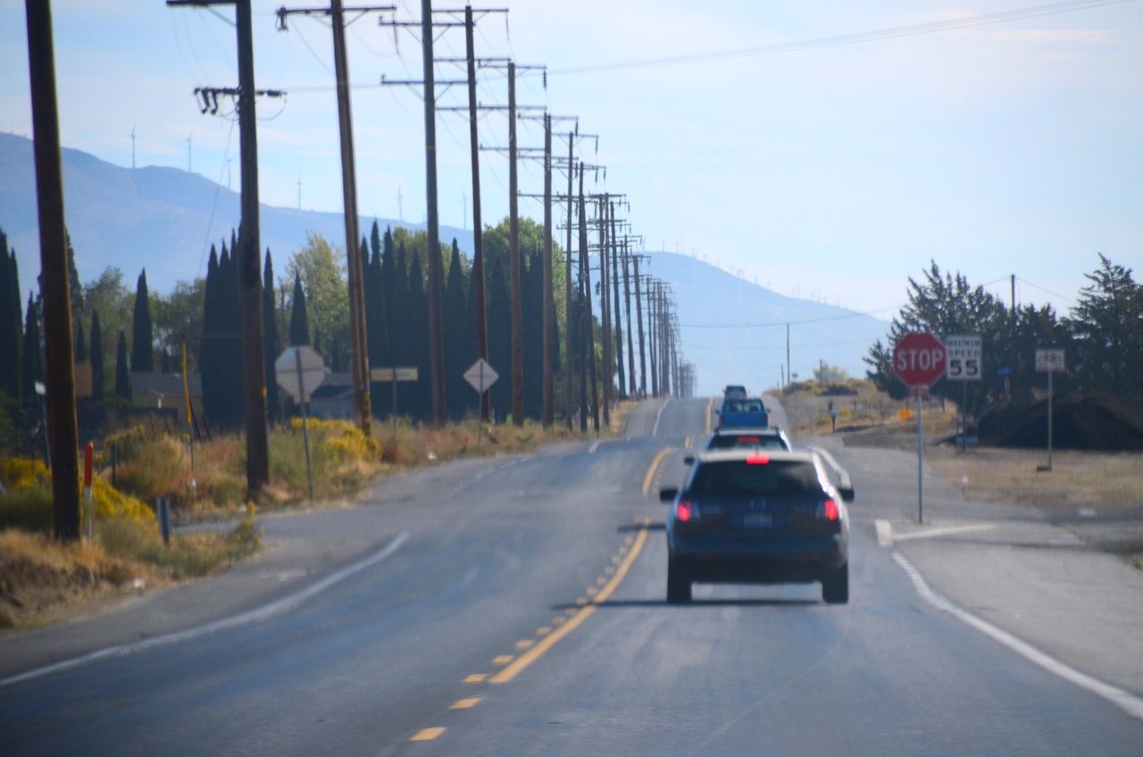 transportation, road, mode of transportation, the way forward, sign, mountain, direction, land vehicle, car, motor vehicle, electricity, nature, sky, road marking, cable, plant, tree, connection, electricity pylon, technology, outdoors, no people, diminishing perspective