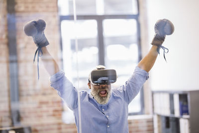 Portrait of businessman with virtual reality glasses and boxing gloves in the office