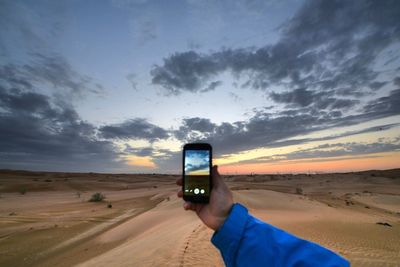 Close-up of man using smart phone against sky