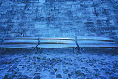 Empty bench against brick wall