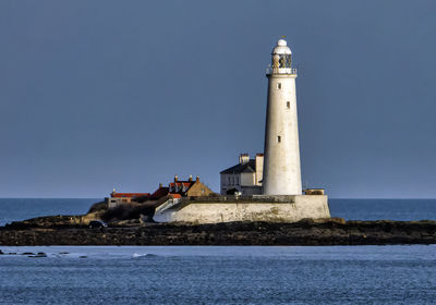 Lighthouse by sea against sky