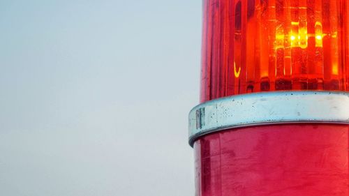 Close-up of red glass against blue sky