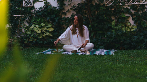 Full length of young woman making herbal medicine while sitting outdoors