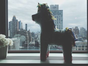 Close-up of paper horse on window sill against city