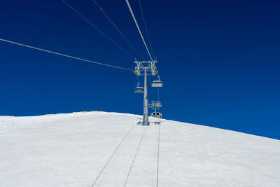 Low angle view of ski lift against clear blue sky