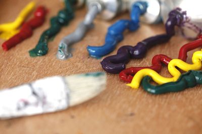 Close-up of colorful paints spilled from tubes on wooden table