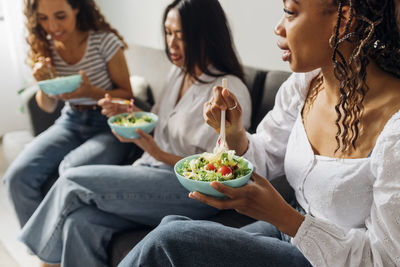 Woman eating salad with friends at home