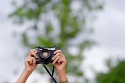 Cropped hands of woman holding camera