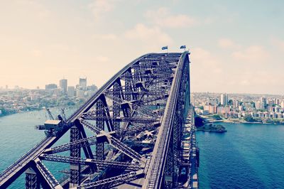 Bridge over river by buildings against sky in city