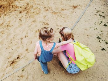 High angle view of mother and daughter on sand at beach