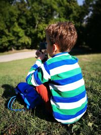 Rear view of boy sitting on field