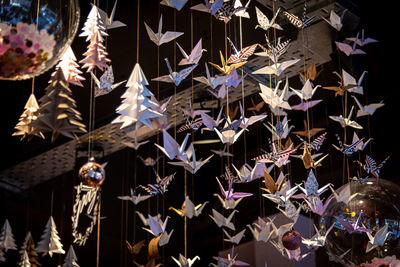 Lots of origami swans hanging from the roof, seen from underneath in a softly illuminated room