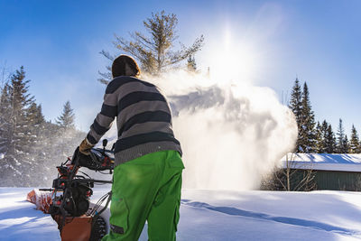 Rear view of person riding horse against sky during winter