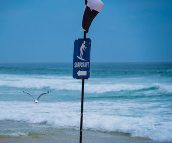 Information sign on beach against clear blue sky