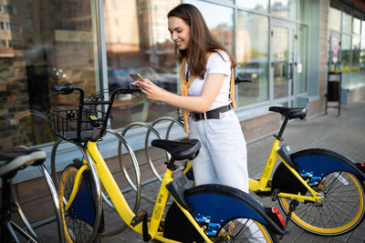 Smiling woman renting bicycle in city