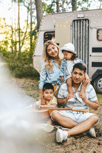 An asian family is vacationing traveling on a road trip by a camper car in the forest in nature