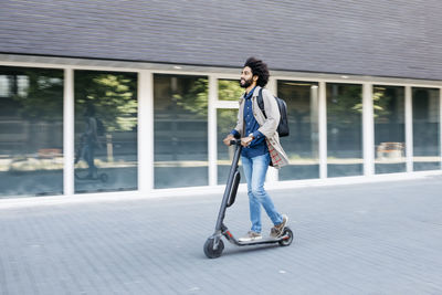 Man with backpack riding fast with his e-scooter in the city