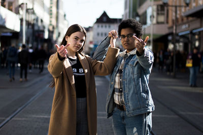 Portrait of couple showing middle finger while standing on city street