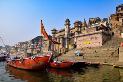 Boats moored in river against buildings