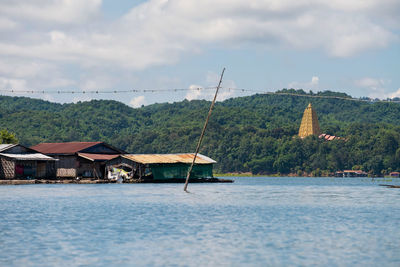 Floating house village at songaria river with bodhgaya pagoda in sangkhlaburi, kanchanaburi