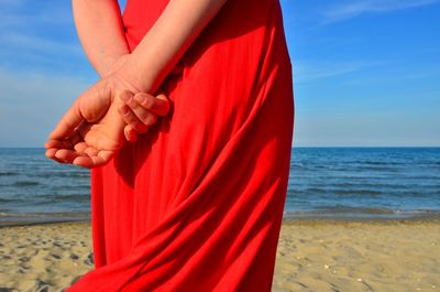 Low section of person on beach against sky