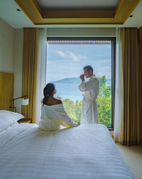 Couple men and women waking up in a hotel room looking out over the ocean